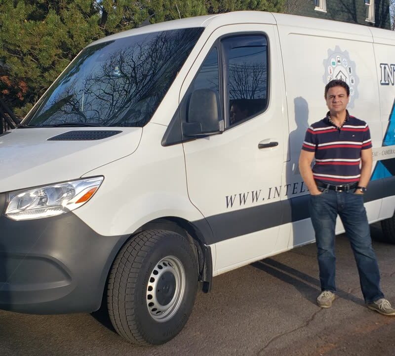 Camionnette aux couleurs d'Intelleco stationnée devant une résidence
